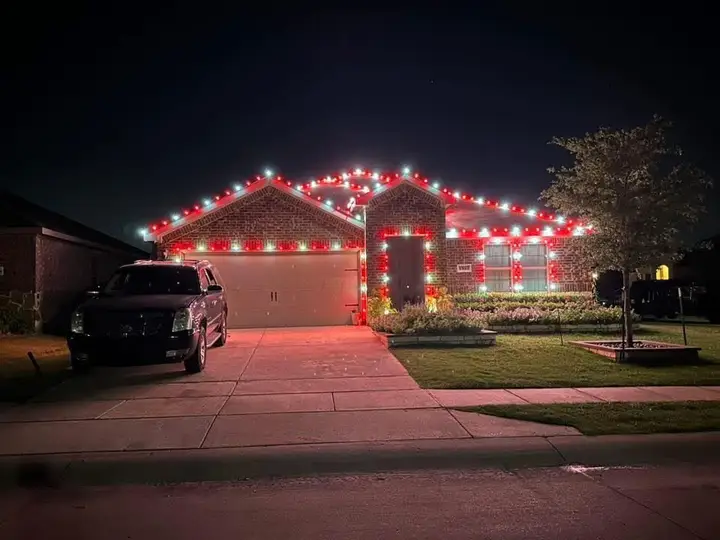 A house outlined in red and white holiday lights at night