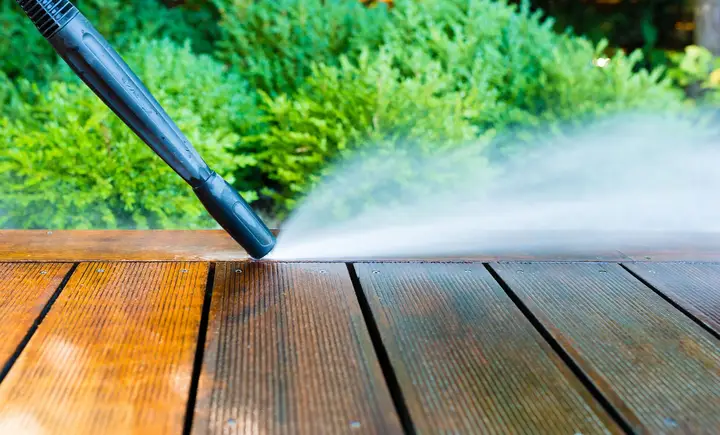 A wash wand cleaning the boards of a wood deck