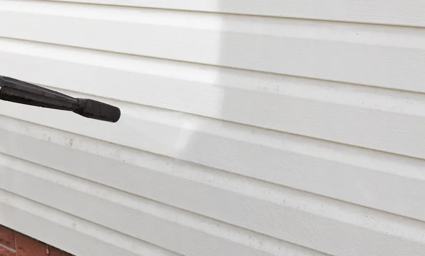 Clean white vinyl siding being rinsed at low pressure