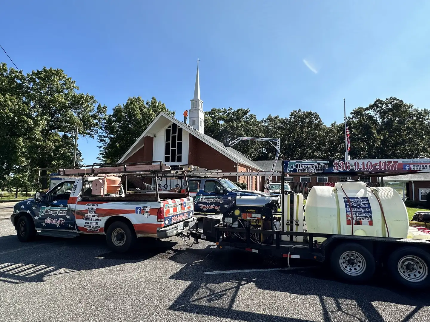 A brick church with a white steeple, with the A1 truck and its tank trailer parked on the road out front