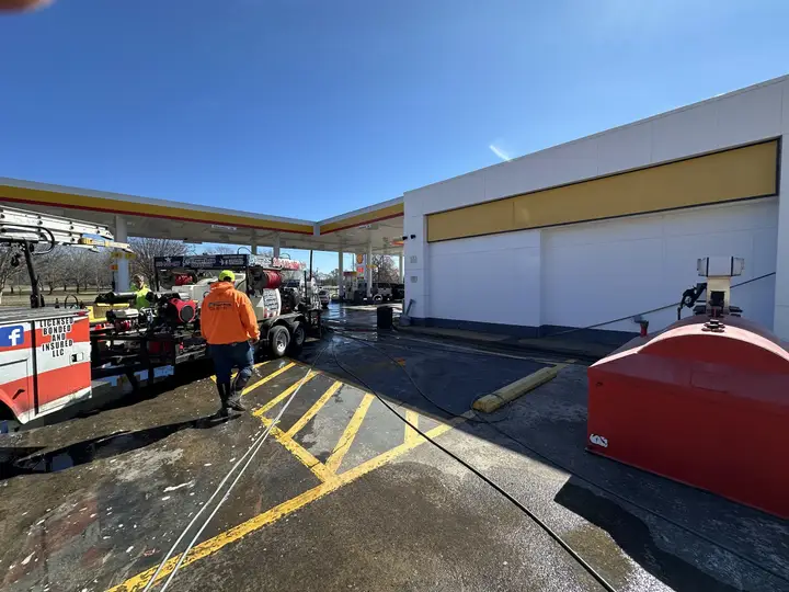 A gas station forecourt being washed, with the A1 truck and trailer parked on the wet pavement