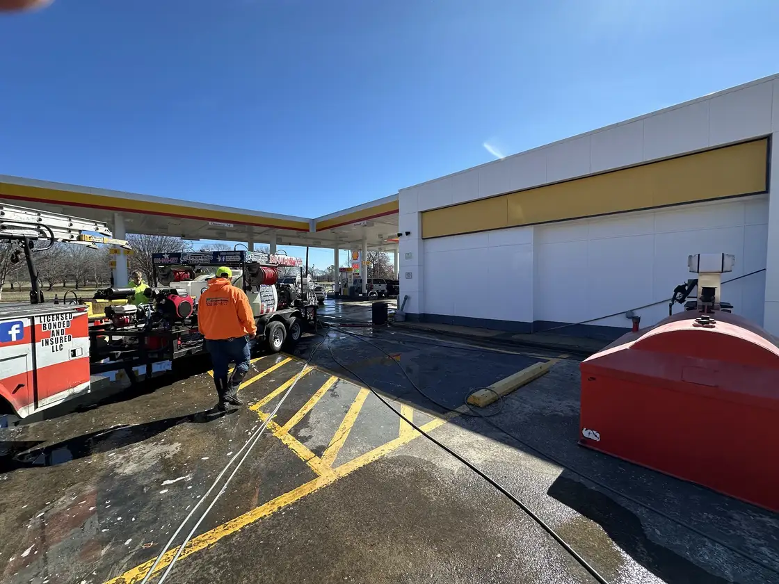 A gas station forecourt being washed, with the A1 truck and trailer parked on the wet pavement