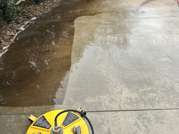 A concrete driveway half washed, with a hard line between the clean side and the dirty side