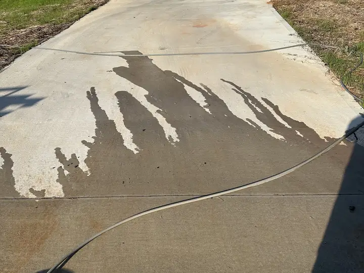 Clean streaks washed across the grime on a concrete driveway
