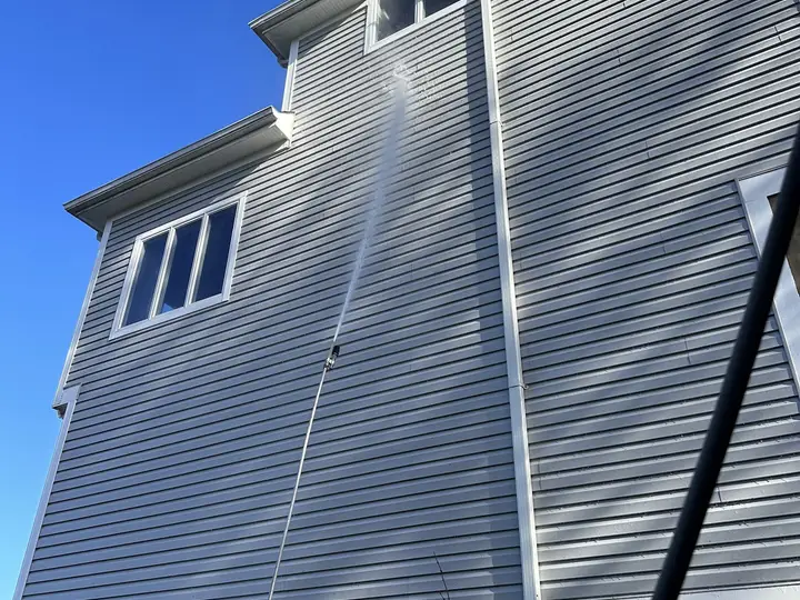 A long arc of water reaching the second story of a house from the ground