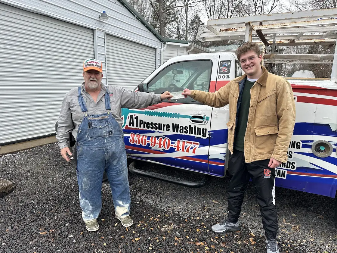 Robert and a younger crew member shaking hands in front of the A1 truck