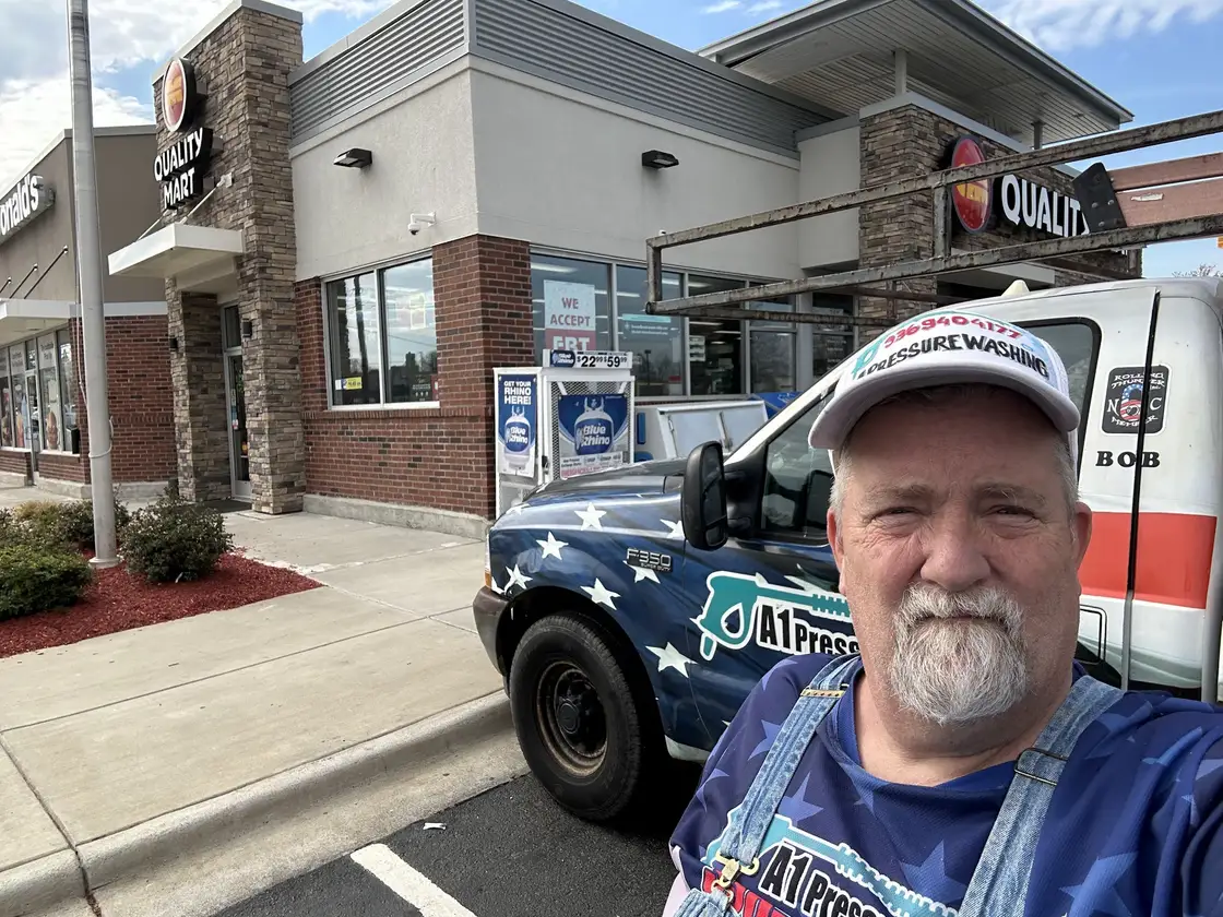 A selfie Robert took of himself in an A1 cap and shirt, with the flag wrapped truck parked behind him at a store
