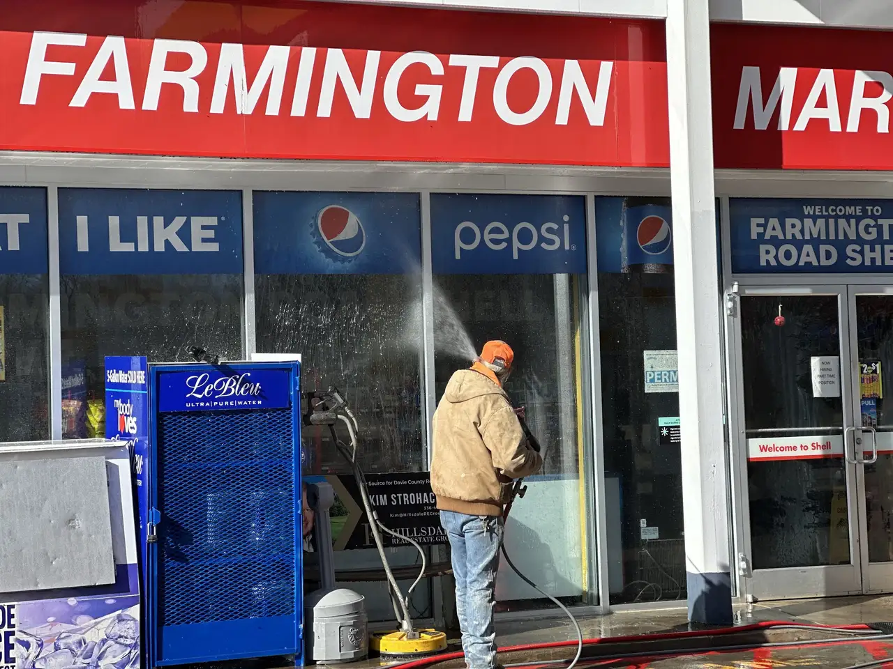 A crew member washing the front glass of a country store